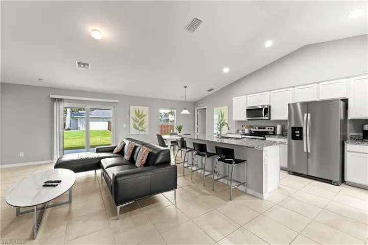 Living room with light tile patterned floors, lofted ceiling, and recessed lighting