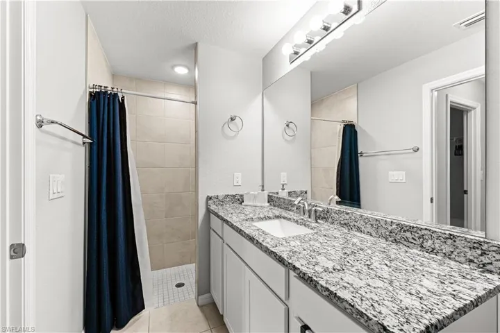 Full bath with vanity, a textured ceiling, a shower stall, and light tile patterned floors