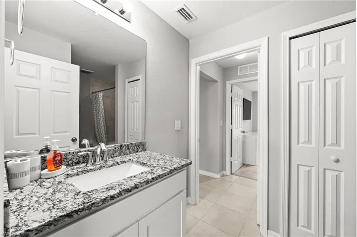 Full bathroom with vanity, a closet, light tile patterned flooring, and a shower with curtain