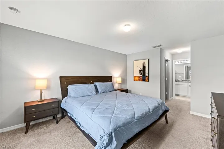 Bedroom with light colored carpet and connected bathroom