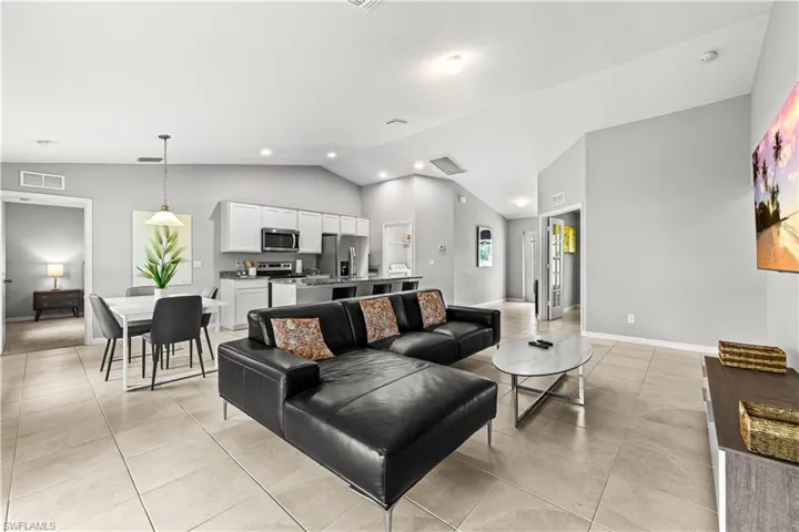 Living area featuring light tile patterned floors, recessed lighting, and high vaulted ceiling