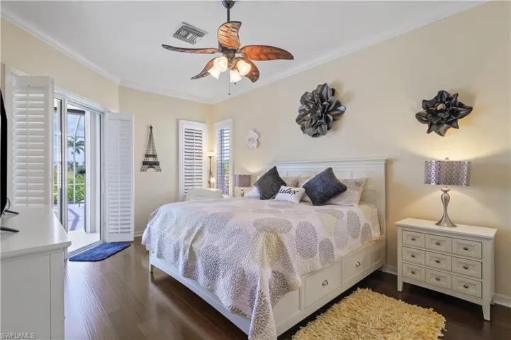 Bedroom with visible vents, baseboards, ornamental molding, a ceiling fan, and dark wood-style floors