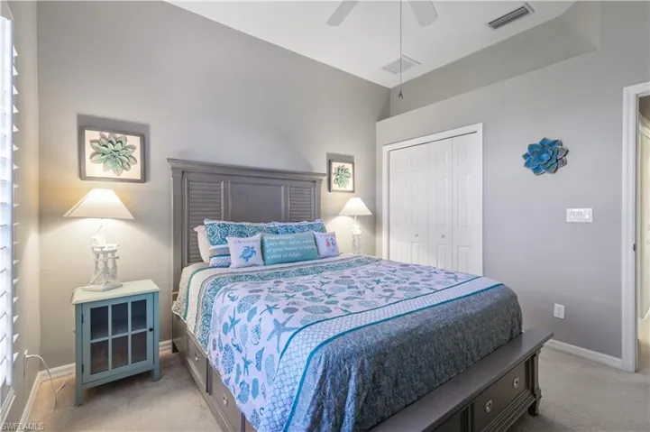 Bedroom featuring a closet, visible vents, baseboards, ceiling fan, and light carpet