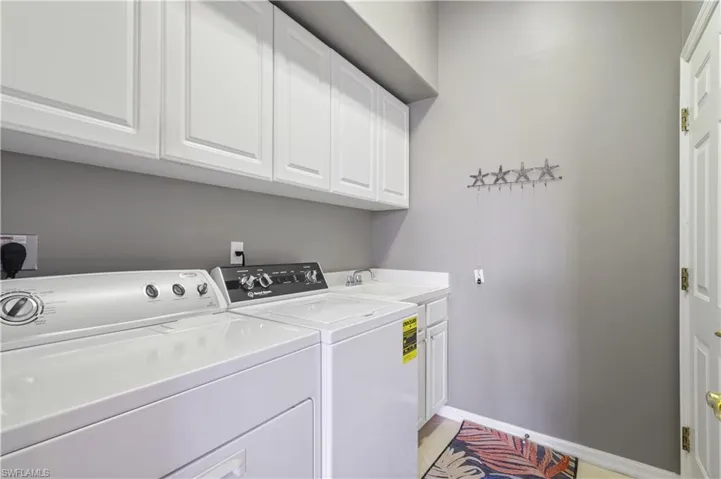 Laundry room with baseboards, cabinet space, washing machine and dryer, and a sink