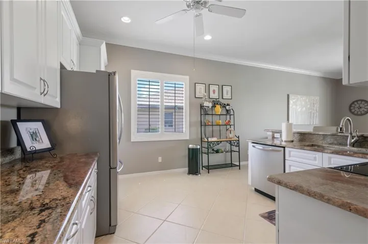 Kitchen with light tile patterned flooring, white cabinets, dishwasher, ornamental molding, and a sink