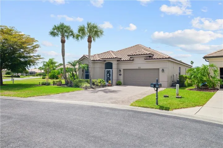 Mediterranean / spanish-style home with driveway, stucco siding, a front lawn, a tiled roof, and a garage