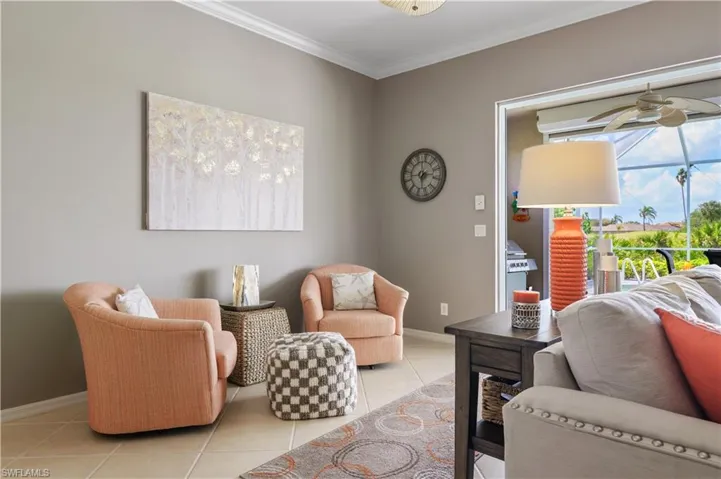 Living room with baseboards, crown molding, ceiling fan, and light tile patterned floors