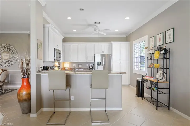 Kitchen with visible vents, a peninsula, ceiling fan, stainless steel appliances, and a breakfast bar area