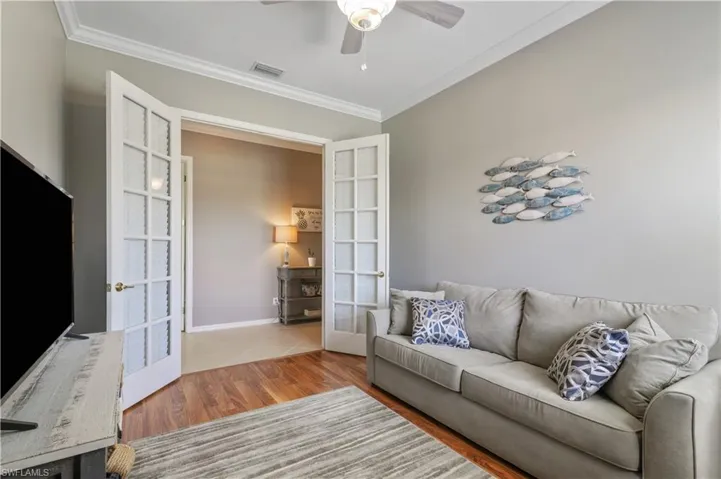 Living room featuring visible vents, ceiling fan, ornamental molding, wood finished floors, and french doors