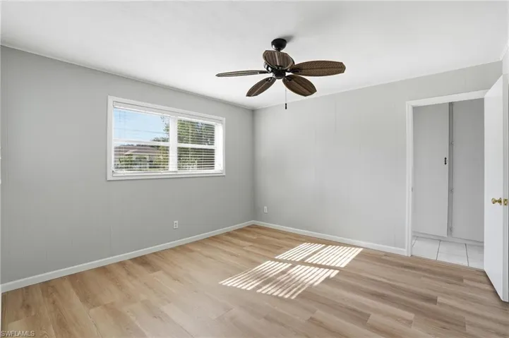 Spare room featuring light wood-style floors, a ceiling fan, and wood walls