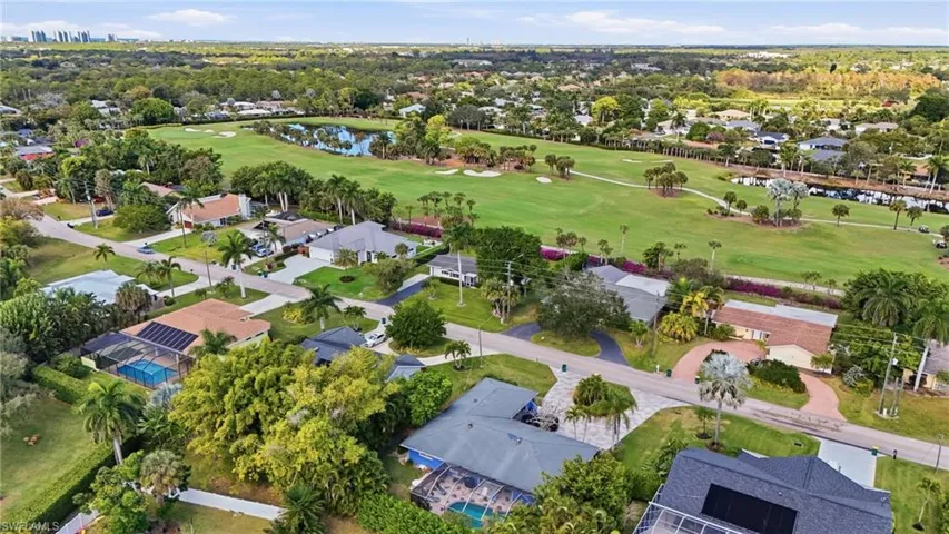 Aerial overview of property's location with nearby suburban area, a local golf course, and a large body of water