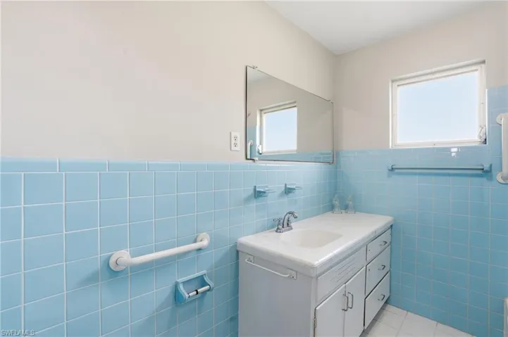 Bathroom featuring a wainscoted wall, vanity, tile walls, and light tile patterned floors