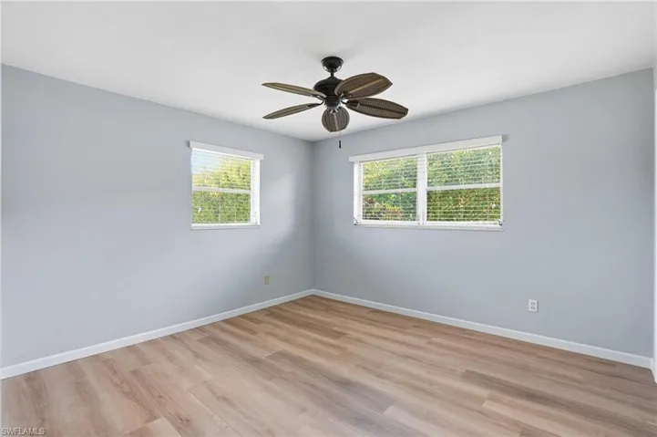Empty room with light wood finished floors, healthy amount of natural light, and a ceiling fan
