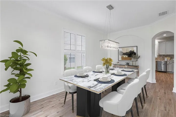 Dining room featuring crown molding, light wood-type flooring, and arched walkways