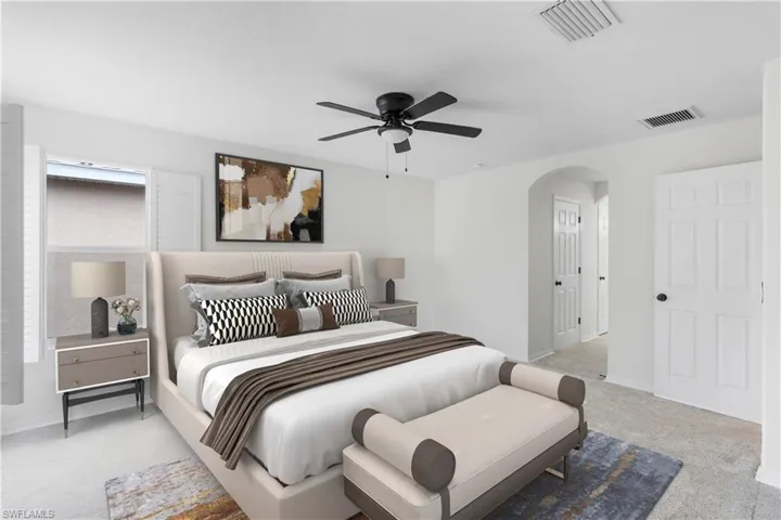 Bedroom with light carpet, arched walkways, and a ceiling fan
