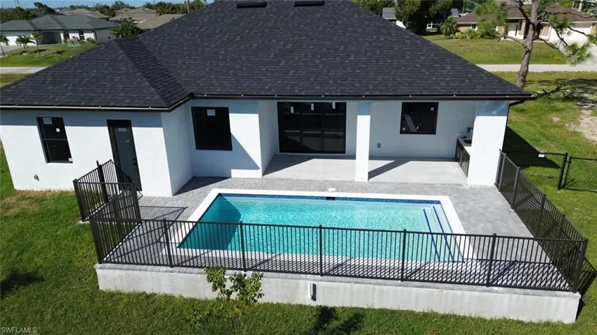 Back of property featuring a patio area, stucco siding, a lawn, and roof with shingles