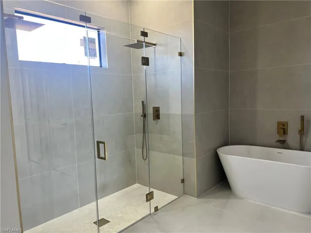 Full bath featuring a shower stall, a soaking tub, and tile walls