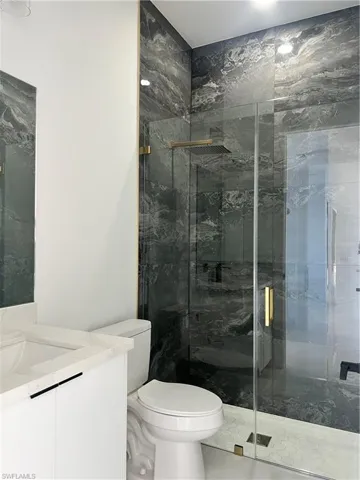Bathroom with vanity and a marble finish shower