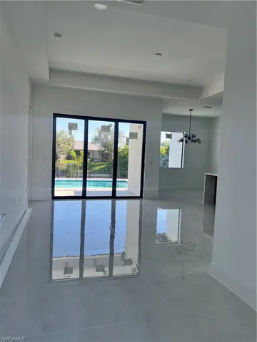 Unfurnished room featuring a chandelier and baseboards