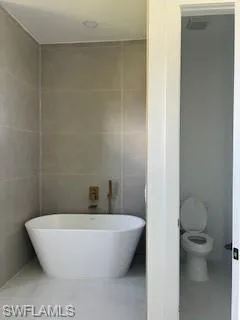 Full bath featuring a freestanding bath, tile walls, and tile patterned flooring