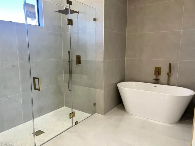 Full bath with a stall shower, a soaking tub, and tile walls