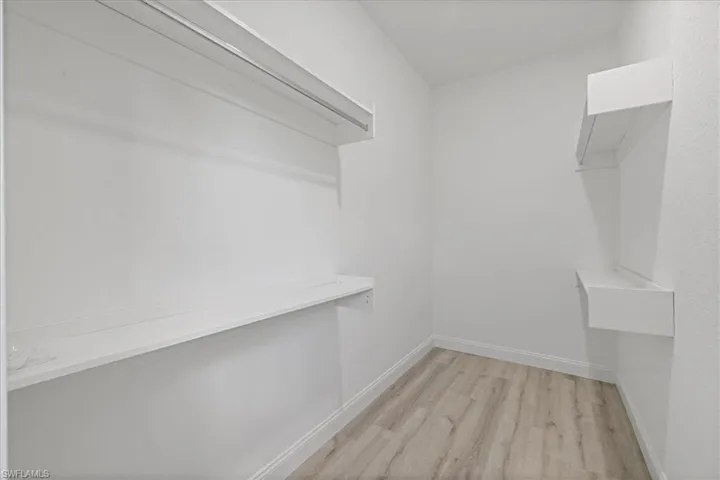Walk in closet with light wood-style floors