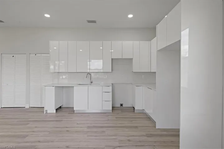 Kitchen with white cabinets, modern cabinets, light wood-style floors, decorative backsplash, and recessed lighting