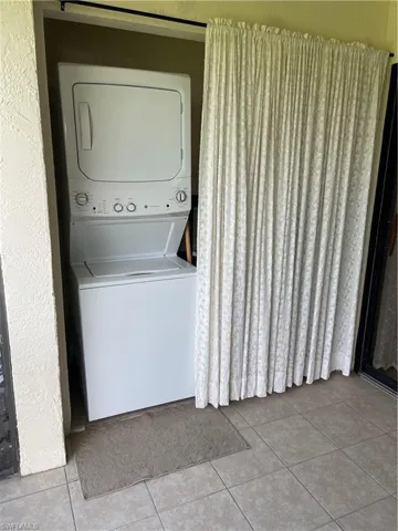 Laundry room with stacked washer / dryer and light tile patterned floors