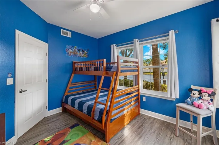 Bedroom featuring a textured wall, wood finished floors, and a ceiling fan