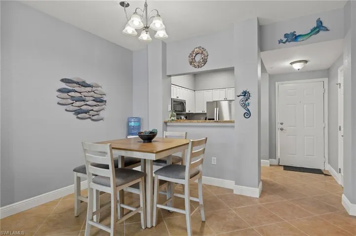Dining space with light tile patterned flooring and a chandelier