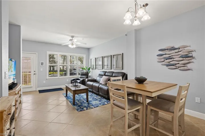 Living area with light tile patterned flooring, a chandelier, and ceiling fan