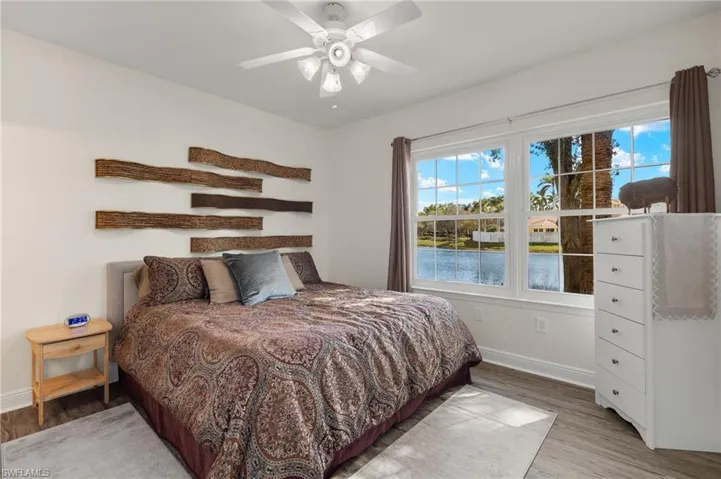 Bedroom with a ceiling fan, light wood-style flooring, and a water view