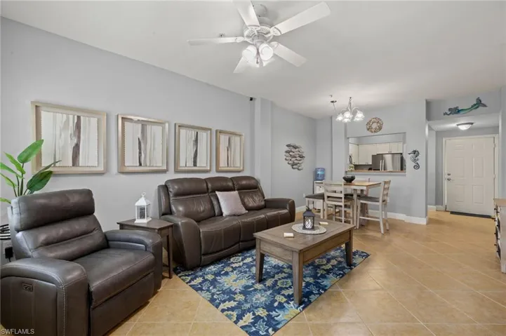 Living room featuring light tile patterned flooring, a chandelier, and a ceiling fan