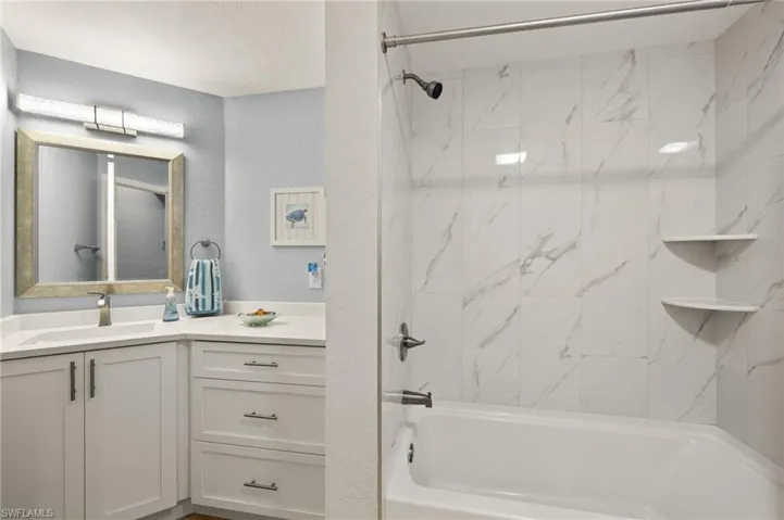 Bathroom with vanity, a textured wall, and shower / washtub combination