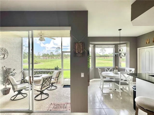 Tiled dining area with ceiling fan with notable chandelier and a wealth of natural light