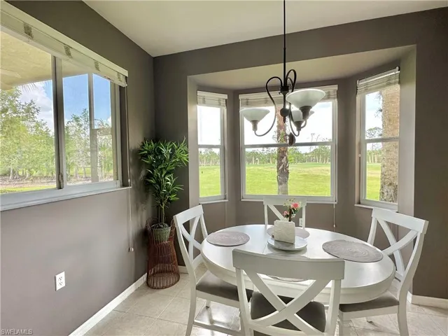 Dining room featuring light tile patterned flooring, a healthy amount of sunlight, and a notable chandelier