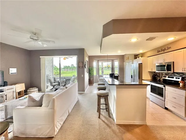 Kitchen with a breakfast bar area, backsplash, stainless steel appliances, white cabinets, and a kitchen island