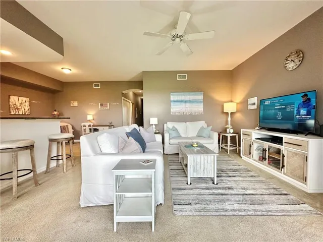 Carpeted living room featuring ceiling fan