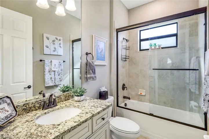 Bathroom with enclosed tub / shower combo, vanity, and toilet