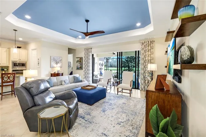 Living area with tray ceiling, ceiling fan and crown molding