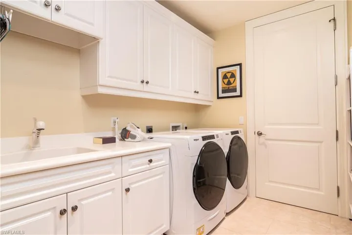 Washroom featuring washer and dryer, cabinet space, and light tile patterned floors