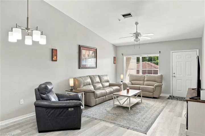 Vaulted ceiling, dining area ready for your table and seating, ceiling fan, white paneled door, modern chandelier