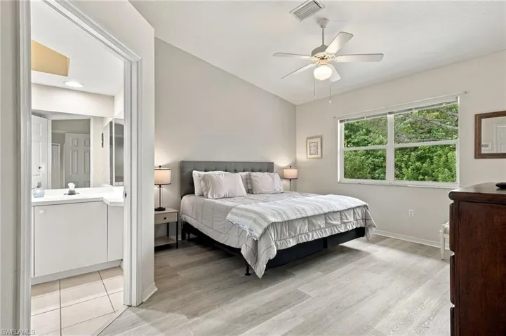 Vaulted ceilings, luxury vinyl tile flooring, and a ceiling fan with integrated lighting, window facing preserve and trees