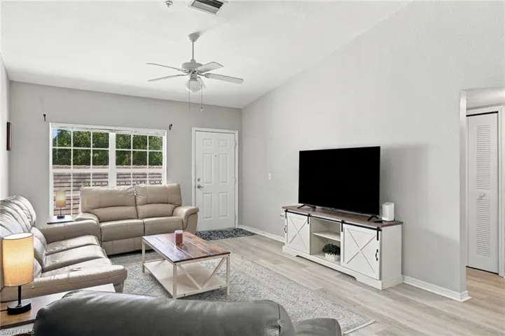 Vaulted ceiling, light flooring, white ceiling fan, multi-pane window, and a white entry door