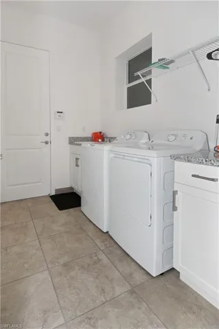 Laundry area featuring cabinet space, washing machine and clothes dryer, and light tile patterned flooring