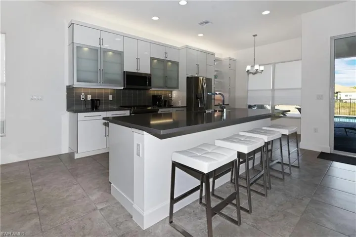 Kitchen featuring a breakfast bar area, stainless steel appliances, dark countertops, a large island, and glass insert cabinets