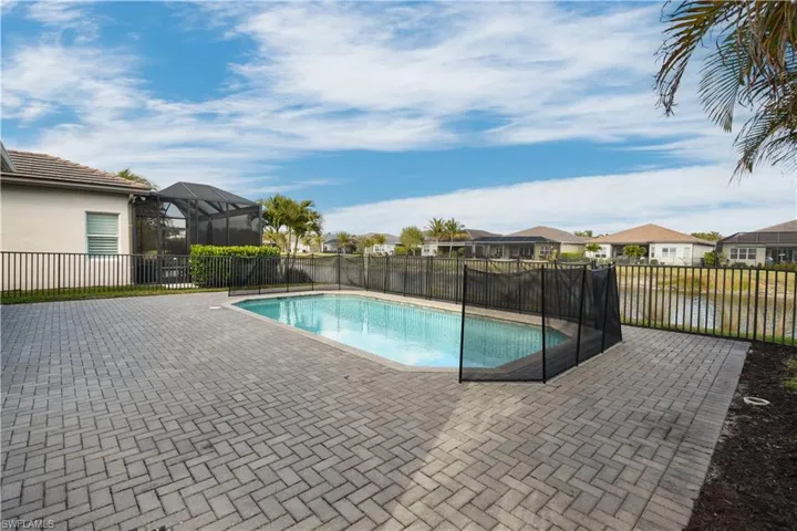 View of swimming pool featuring patio surround, a residential view, a fenced backyard, and a lanai
