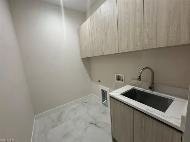 Laundry room featuring hookup for a washing machine, sink, cabinets, and electric dryer hookup