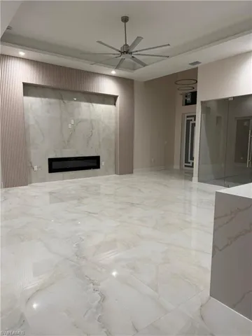 Unfurnished living room featuring ceiling fan and a premium fireplace