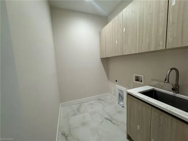 Clothes washing area with electric dryer hookup, hookup for a washing machine, sink, and cabinets